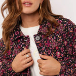 Close-up van model met Fluresk Mirabel Jacket met kleurrijke bloemenprint in roze en paars.