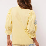Achterkant van de Fluresk Marlowe blouse in geel met pofmouwen en bijpassende short.