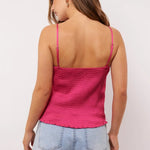 Close-up van de achterkant van de Millicent top in roze satijn met gesmokte stretchstof en verstelbare bandjes, gecombineerd met een denim short.
