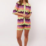 Model draagt de complete co-ord set met Rihanna Shorts en Whitney blouse van Fluresk – kleurrijke zomerse outfit in gehaakt zigzagmotief.