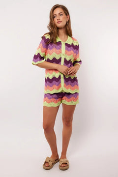 Model draagt de complete co-ord set met Rihanna Shorts en Whitney blouse van Fluresk – kleurrijke zomerse outfit in gehaakt zigzagmotief.