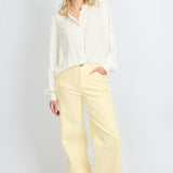 Model draagt de Verina Pants van fluresk in het butter yellow met een hoge taille voor dames samen met de Yailin blouse met pofmouwen in het off-white.