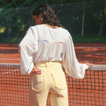 Model draagt de Verina Pants van fluresk in het butter yellow met een hoge taille voor dames samen met de Yailin blouse met pofmouwen in het off-white.