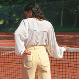 Model draagt de Verina Pants van fluresk in het butter yellow met een hoge taille voor dames samen met de Yailin blouse met pofmouwen in het off-white.