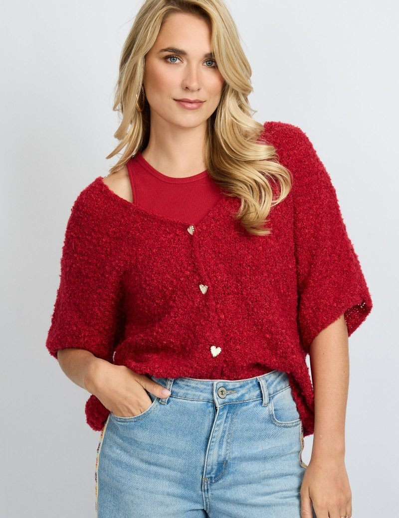 model draagt het fluresk yela vest in een rode kleur met hartjes knopen en een v-hals.