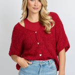 model draagt het fluresk yela vest in een rode kleur met hartjes knopen en een v-hals.