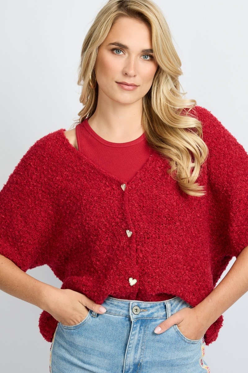 model draagt het fluresk yela vest in een rode kleur met hartjes knopen en een v-hals.