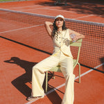 Model draagt de verina pants in het butter yellow en het zeni gilet in het butter yellow in een zomerse setting.