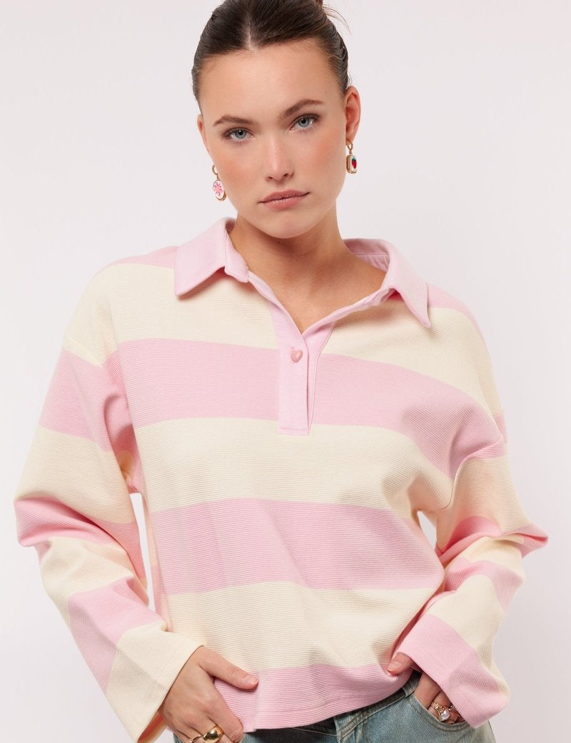 model draagt de fluresk zeyna sweater in het wit met roze en hartjes knoopje.
