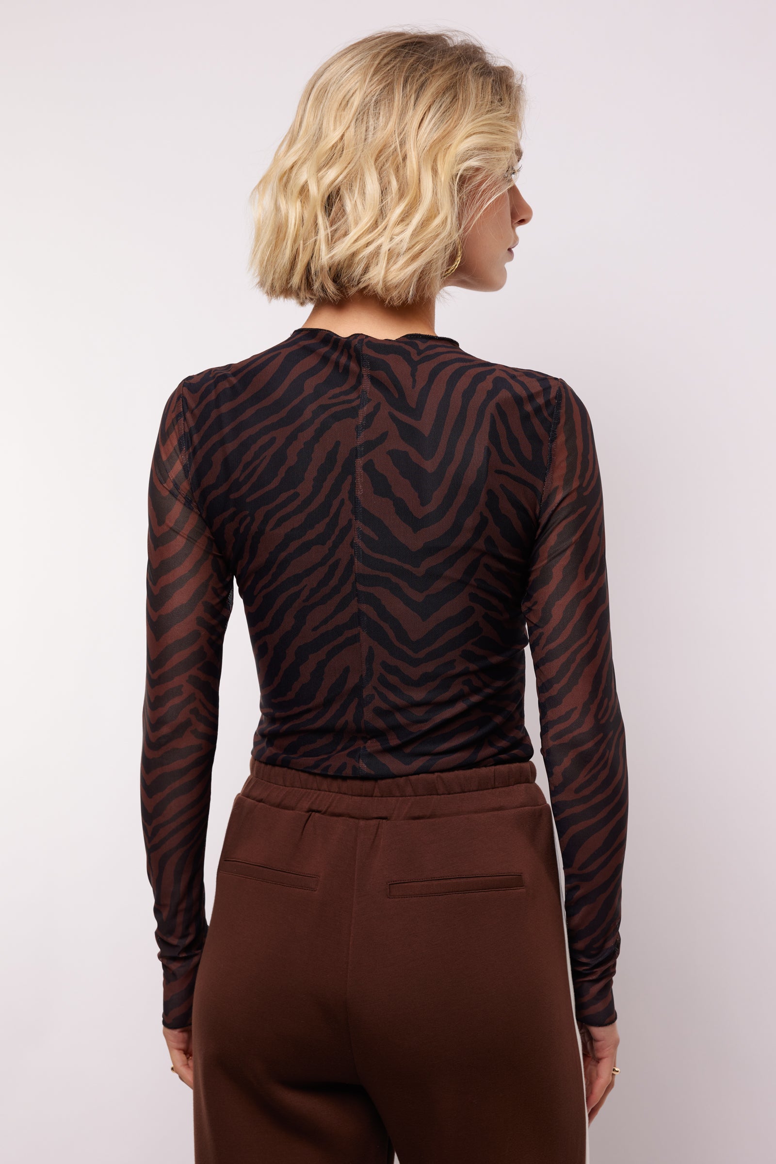 model draagt de lawrence top van fluresk in mocha bruin en zwart.