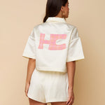 Jas HEYB Club Bowy Jacket Crème – Crèmekleurig cropped jasje met roze HC logo op de rug | Jo&Co Club