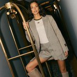 Campagnebeeld HEYB Club FW26: HC longsleeve grey/green van HEYB Club onder een geruite blazer | Jo&Co Club
