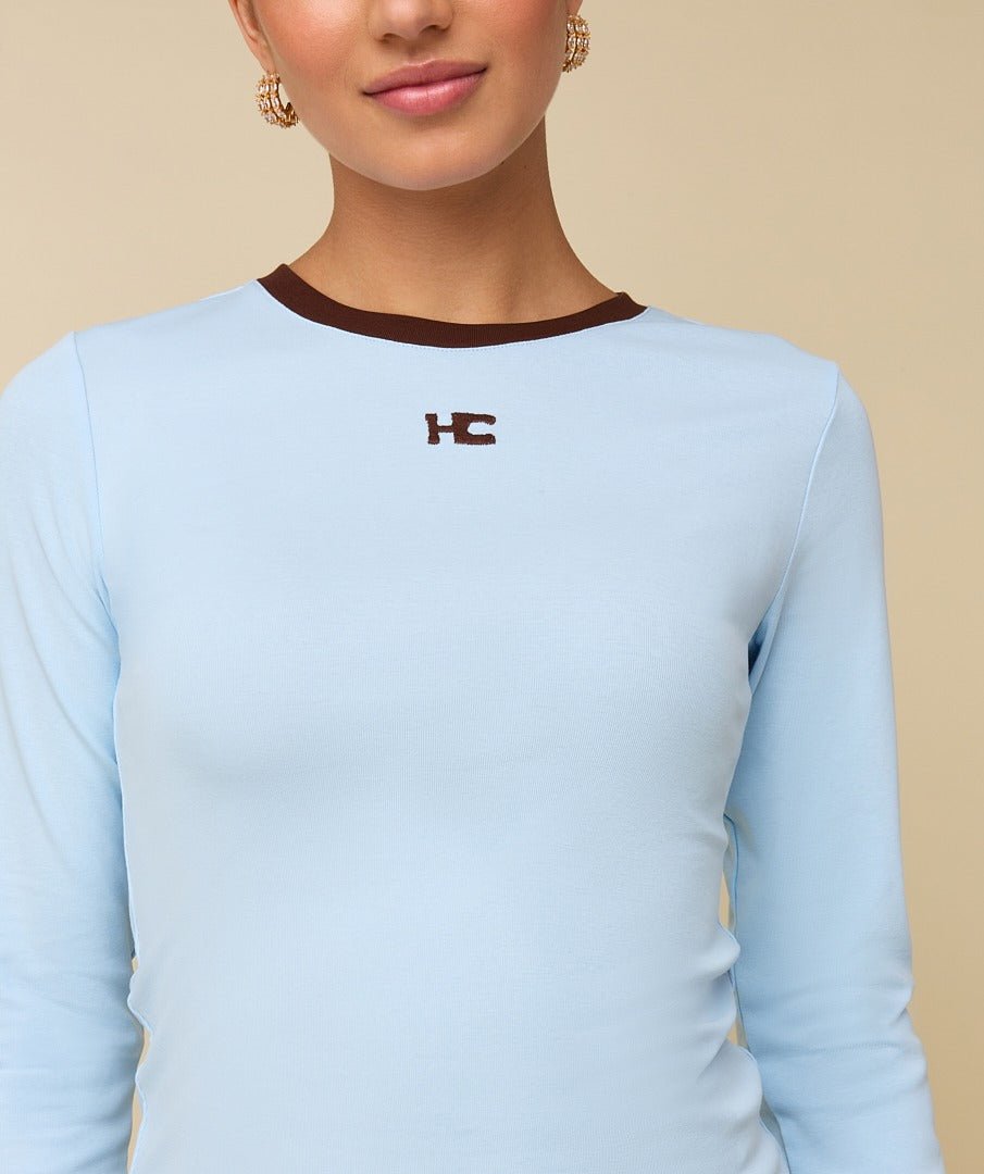 Model in lichtblauwe longsleeve met bruine randjes HEYB Club | Jo&Co Club