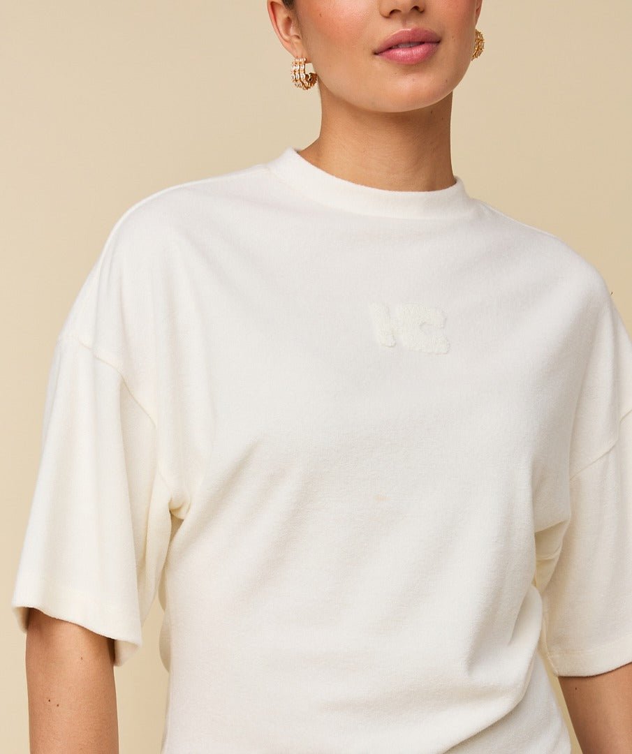 Model in crème boxy t-shirt met logo HEYB Club, andere kant | Jo&Co Club