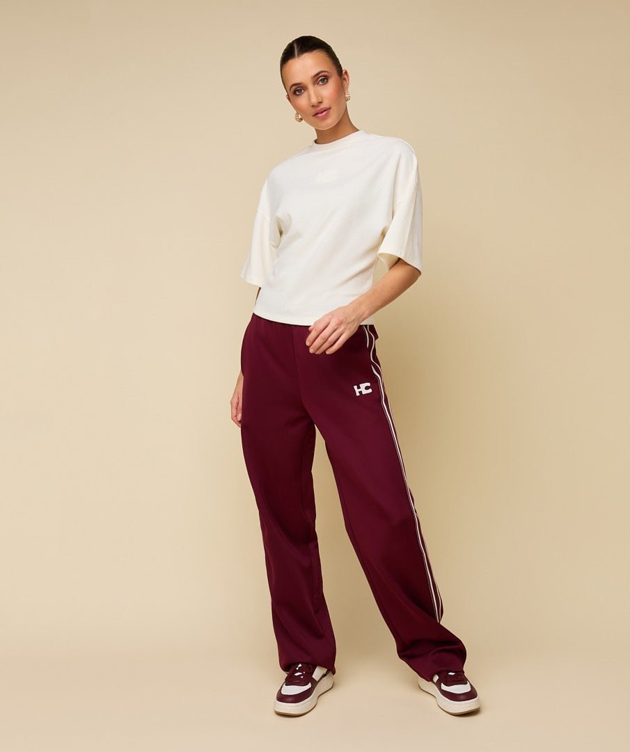 Model in crème boxy t-shirt met logo HEYB Club, andere kant | Jo&Co Club
