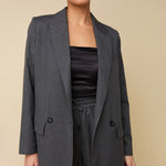 Model in grijze krijtstreep blazer HEYB Club Flo, andere kant | Jo&Co Club