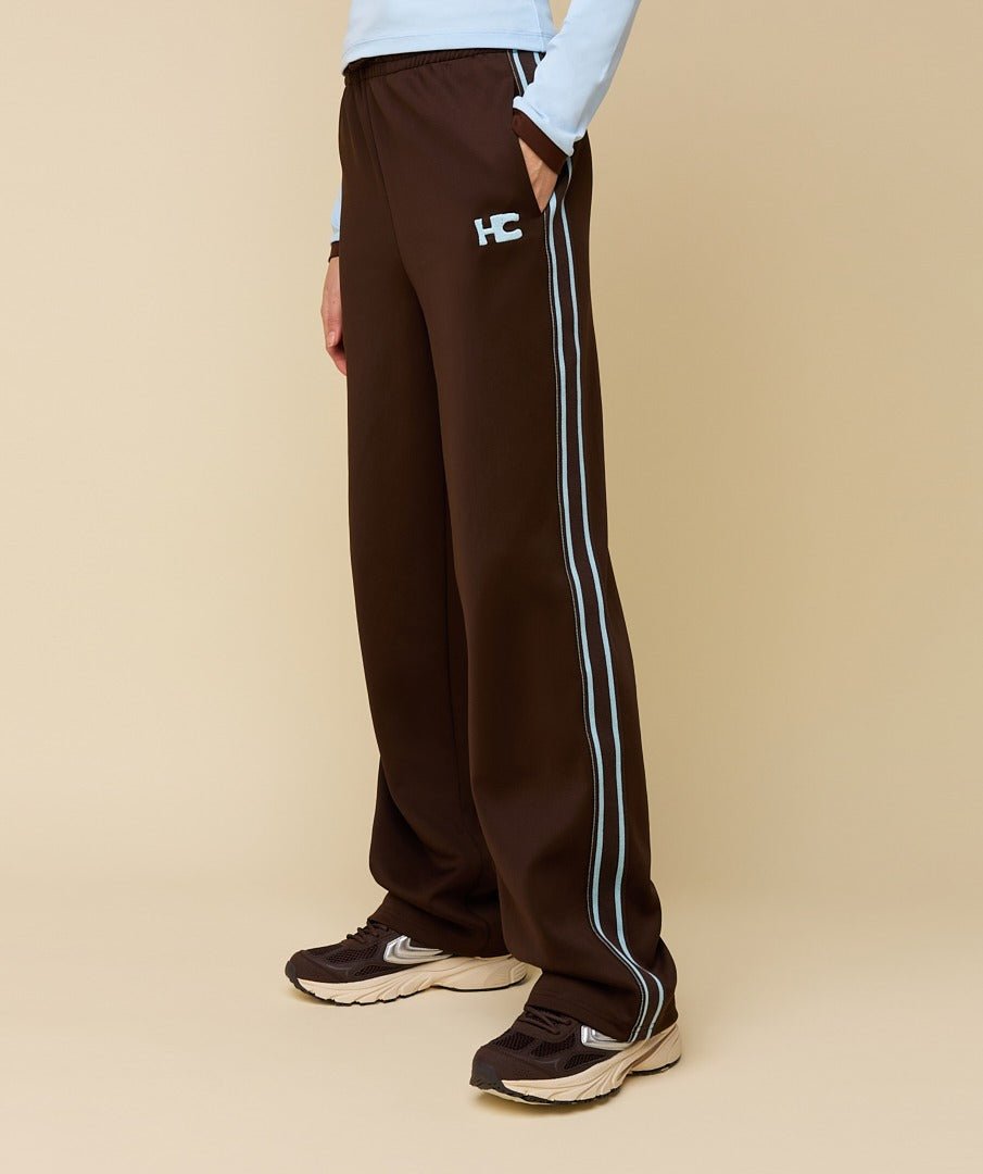 Model in bruine trainingsbroek met lichtblauwe bies HEYB Club Fallon | Jo&Co Club