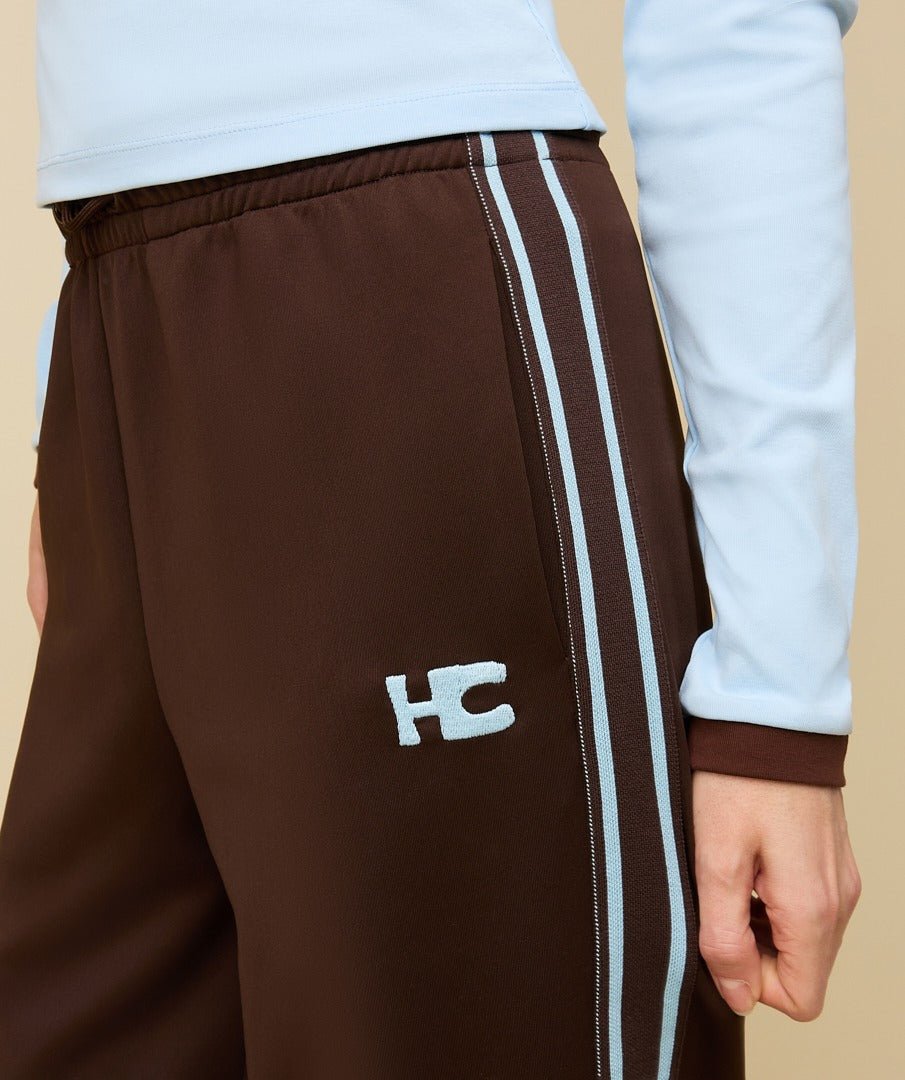 Model in bruine trainingsbroek met lichtblauwe bies HEYB Club Fallon, andere kant | Jo&Co Club