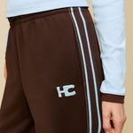 Model in bruine trainingsbroek met lichtblauwe bies HEYB Club Fallon, andere kant | Jo&Co Club