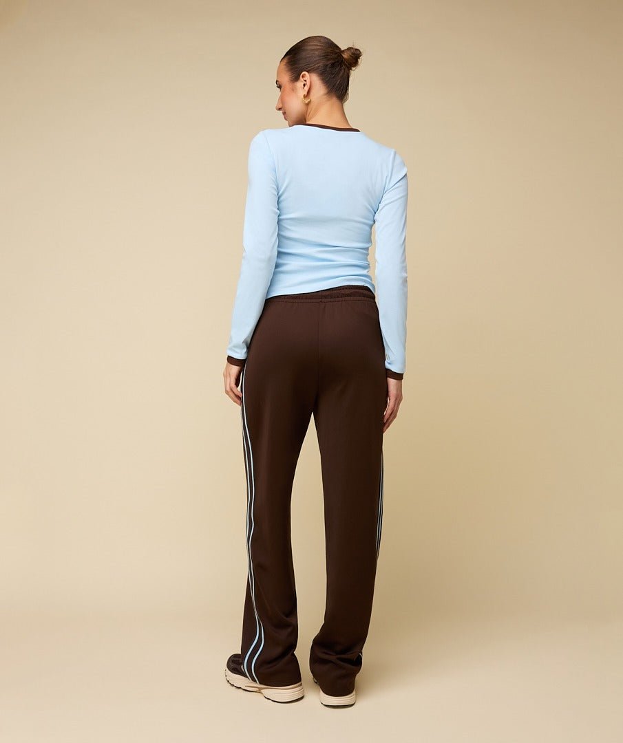 Model in bruine trainingsbroek met lichtblauwe bies HEYB Club Fallon, andere kant | Jo&Co Club