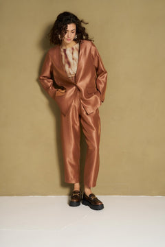 Model in caramel satijnen broek en bijpassende blazer