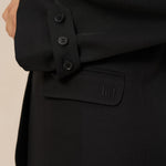 Detail zwarte blazer Jadie – mouwlipje met drie knoopjes en klepzak met logo | Jo&Co Club