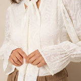 Crème blouse met strik Lofty Manner Jett – close-up van de strik aan de kraag en jacquard met bladmotief | Jo&Co Club