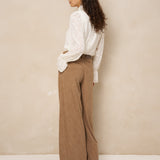 Model van achteren in crème blouse Jett en bruine broek met wijde pijpen | Jo&Co Club