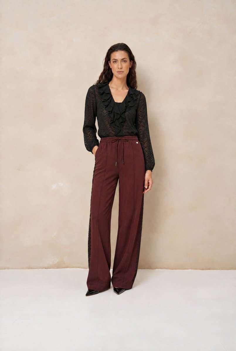Model in broek Lofty Manner Koya met zwarte blouse met ruches | Jo&Co Club