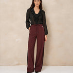 Model in broek Lofty Manner Koya met zwarte blouse met ruches | Jo&Co Club