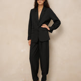 Model in zwarte pantalon Jax met dichtgeknoopte enkels in ballonvorm en blazer Jadie | Jo&Co Club