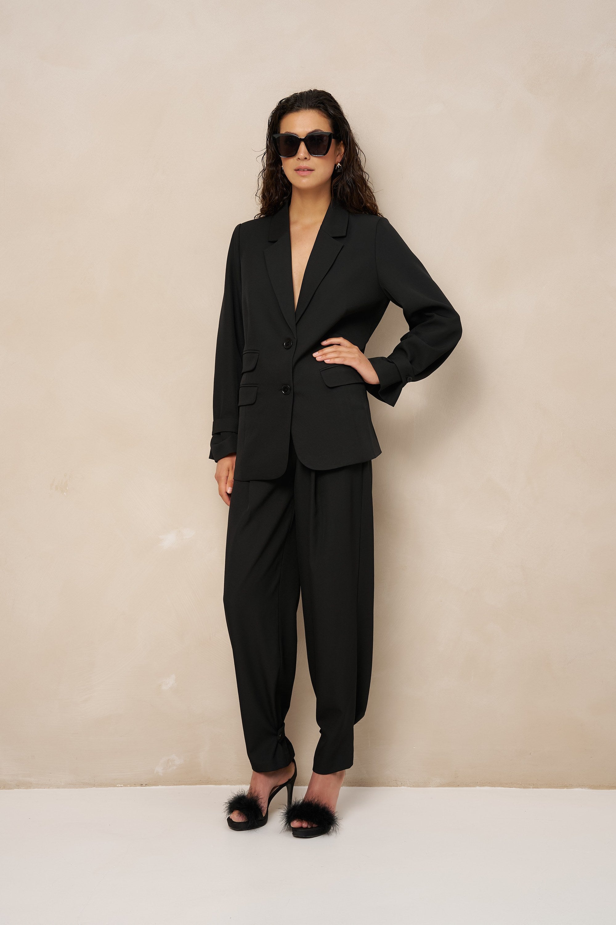 Model in zwarte pantalon Jax met dichtgeknoopte enkels in ballonvorm en blazer Jadie | Jo&Co Club