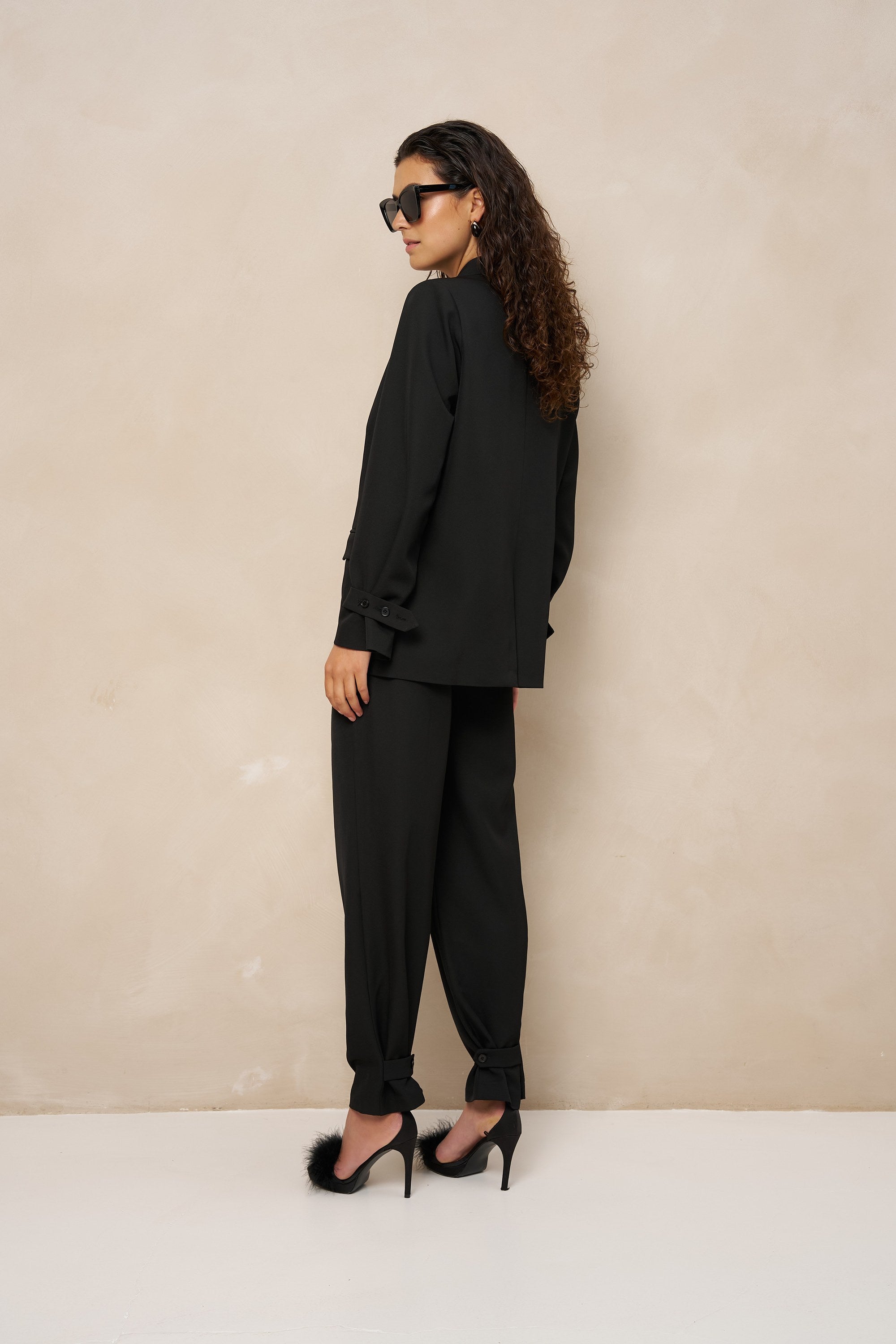 Model van opzij in zwarte pantalon Jax met ingenomen enkels en zonnebril | Jo&Co Club