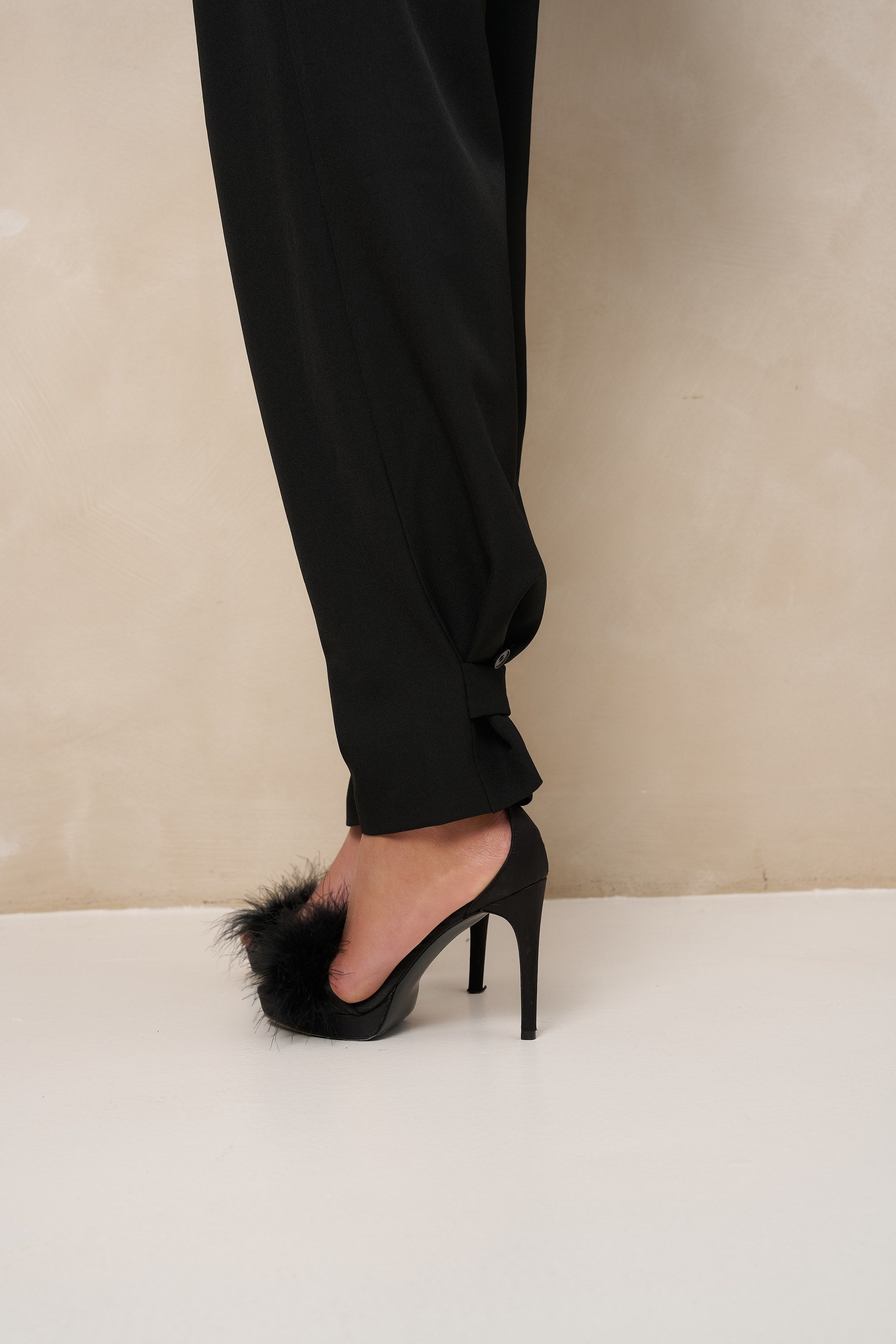 Detail zwarte pantalon Jax – dichtgeknoopt lipje trekt de pijp in bij de enkel | Jo&Co Club
