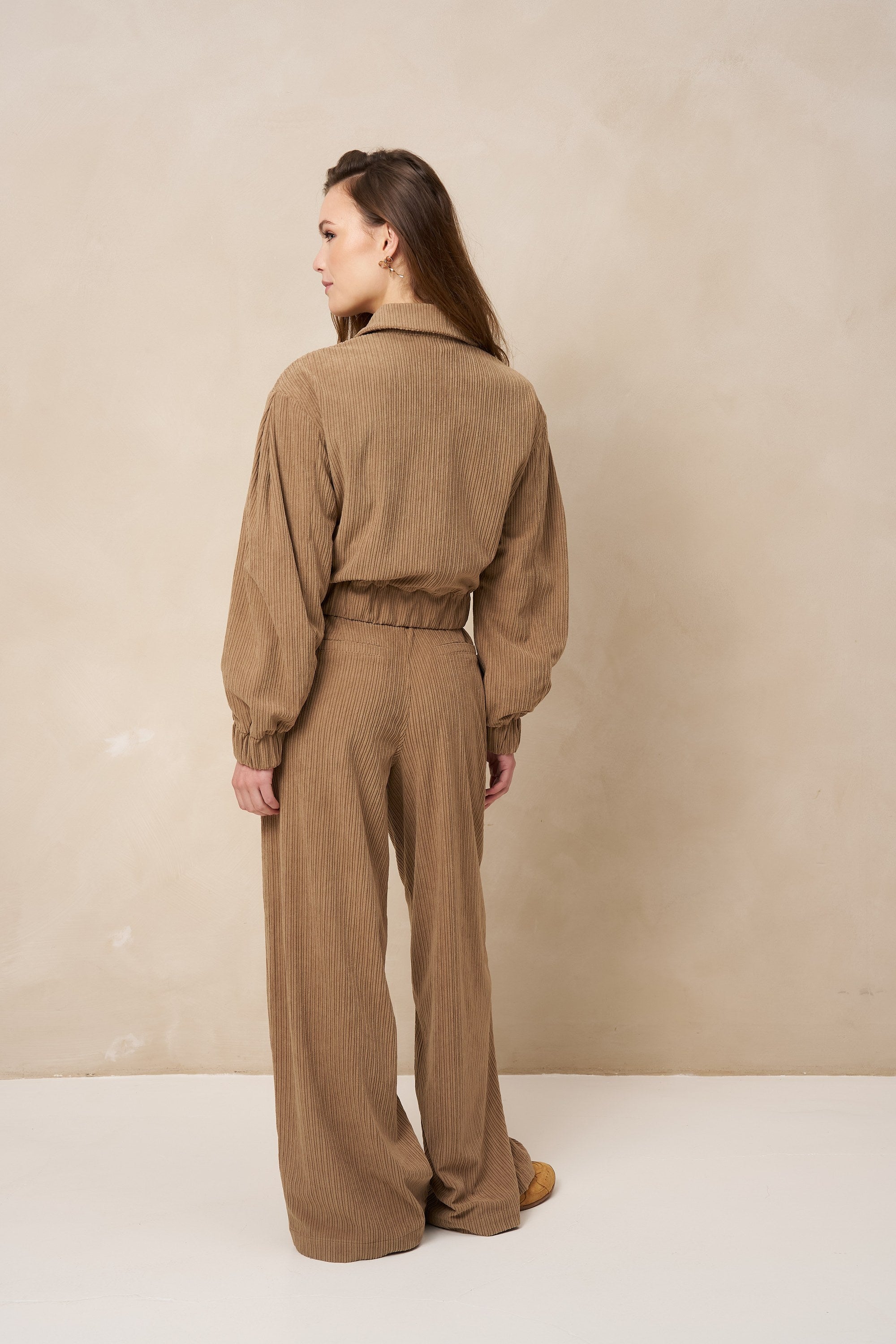 Model van achteren in taupe ribcord broek Josy en bijpassend jasje Jaxy | Jo&Co Club