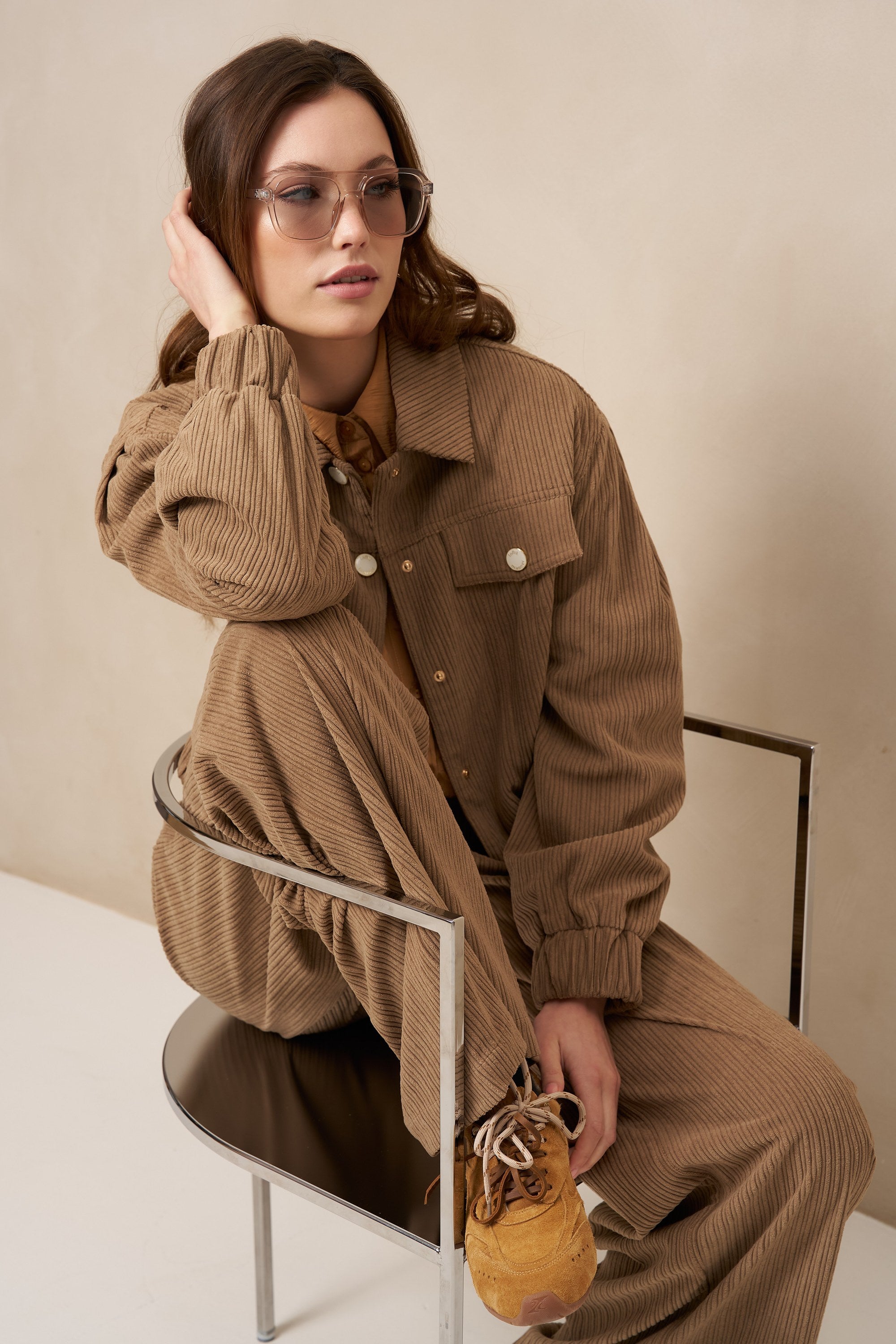 Model zittend in taupe ribcord set Josy en Jaxy met zonnebril | Jo&Co Club