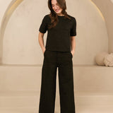 model draagt de dora trouser en de eva top van lofty amnner, het is een co-ord set in het zwart met glinstering.