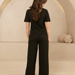 model draagt de dora trouser en de eva top van lofty amnner, het is een co-ord set in het zwart met glinstering.