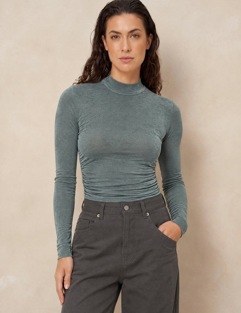 Col top met plooien Lofty Manner Kelly in donker mintgroen, ingestopt in een grijze jeans | Jo&Co Club