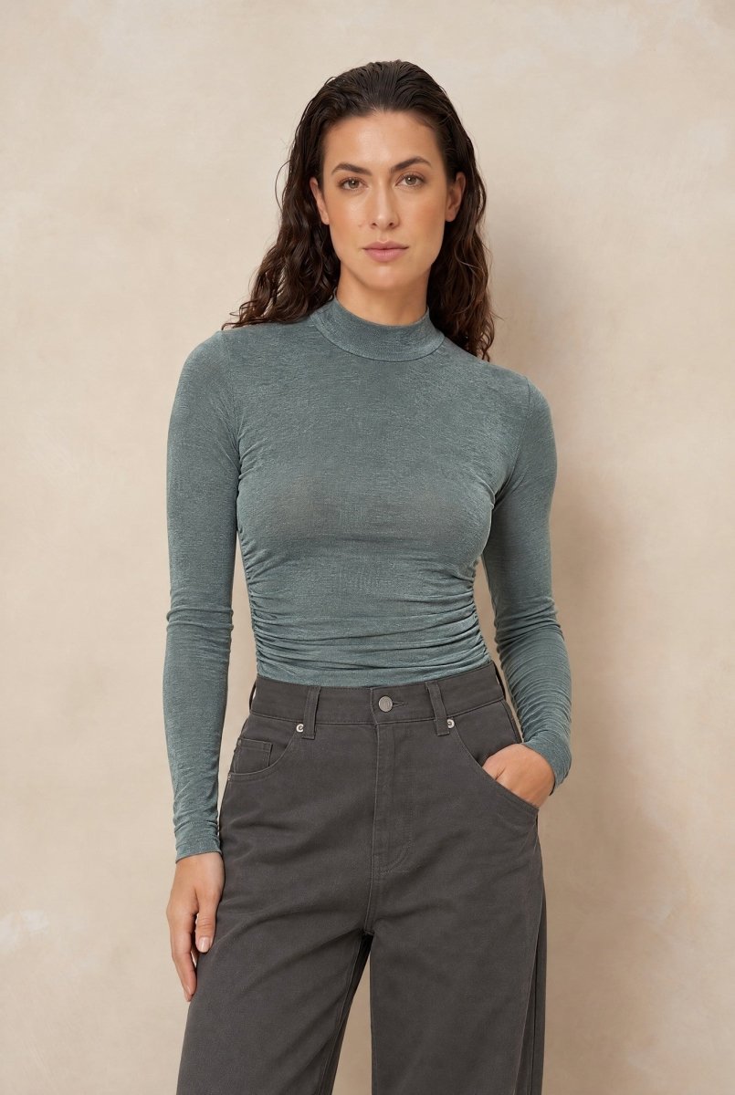 Col top met plooien Lofty Manner Kelly in donker mintgroen, ingestopt in een grijze jeans | Jo&Co Club