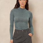 Col top met plooien Lofty Manner Kelly in donker mintgroen, ingestopt in een grijze jeans | Jo&Co Club
