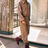 Campagnefoto: model in taupe kunstleren jack Jillie met bijpassende broek en bordeaux laarzen | Jo&Co Club