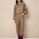 Model in taupe kunstleren jack Jillie met bijpassende broek en bordeaux laarzen | Jo&Co Club