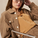 Model zittend in taupe ribcord jasje Jaxy met okergele blouse en zonnebril | Jo&Co Club