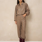 Model in taupe kunstleren jack Jillie met bijpassende broek en bordeaux laarzen | Jo&Co Club