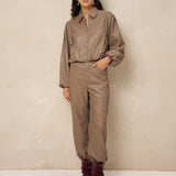 Model in taupe kunstleren jack Jillie met bijpassende broek en bordeaux laarzen | Jo&Co Club