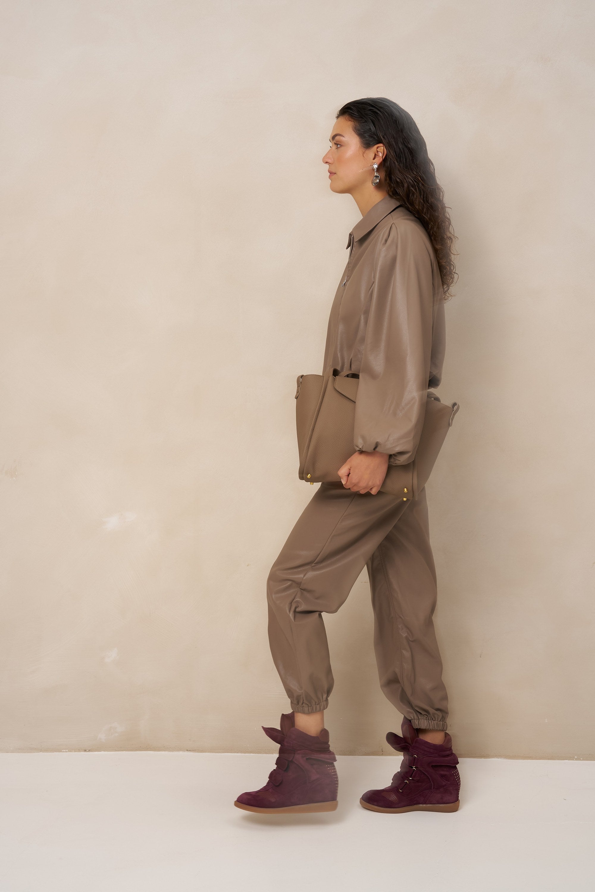 Model van opzij in taupe kunstleren jack Jillie met taupe clutch | Jo&Co Club