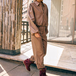 Campagnefoto: model in taupe kunstleren jack Jillie met bijpassende broek en bordeaux laarzen | Jo&Co Club