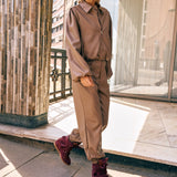 Campagnefoto: model in taupe kunstleren jack Jillie met bijpassende broek en bordeaux laarzen | Jo&Co Club