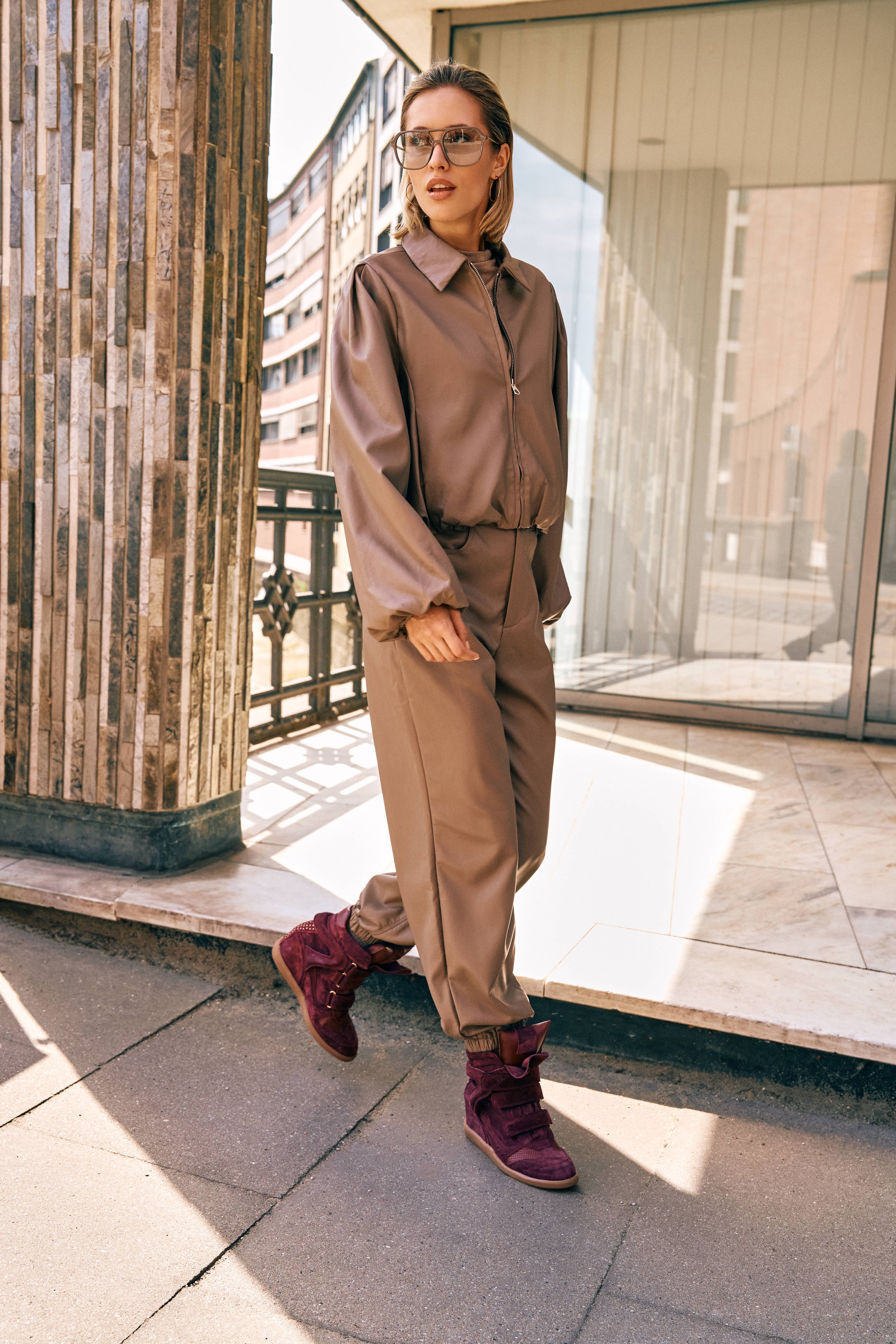 Campagnefoto: model in taupe kunstleren jack Jillie met bijpassende broek en bordeaux laarzen | Jo&Co Club
